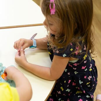 Maedchen spielt mit Knetmassse im Kindergarten